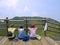 Three girls sitting on observation deck looking at mountains