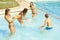 Three girls splashing boy with water guns in pool