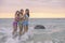 Three girls standing on the rocks, shocked by joyful splashing of sea at sunset on Nai Thon Beach, Phuket, Thailand. sea in the