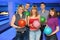 Three girls and two men hold ball for bowling