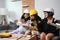 Three girls wearing hard hat pretend to be engineer while playing together in living room.