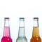 Three glass bottles with multicolored beer, drink, soda on a white background