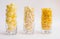 Three glass glasses filled with popcorn, corn flakes and corn sticks. A light, delicious snack. Corn products