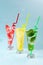 Three glasses of chilled drinks on a blue background, lemonade, watermelon lemonade, mint lemonade, iced drinks