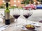 Three glasses of red wine, bottle of wine and chef`s compliment, small plate of paella served on table outdoor terrace
