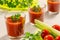 Three glasses of tomato juice decorated with parsley or coriander leaves. Next is a plate of parsley, tomatoes and celery stems