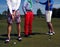 Three golf players on green field.