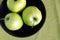 Three green apples inside purple bowl closeup