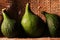 THREE GREEN FIGS ON A SHELF ON A PIECE OF ROUGH HESSIAN