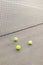 three green tennis balls stand next to tennis net