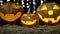 Three halloween pumpkins with eerie faces burning . Black bokeh background. Close up