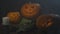 Three Halloween Pumpkins head lantern with extinct candles on a black background on wooden table with knife and spoon