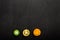 Three halves of a green, yellow, orange tomato lie on a black background. Top view, flat lay