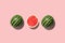 Three halves of watermelon in a row isolated on pink background.