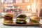 Three hamburgers on wooden board.