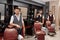 Three handsome barbers posing in barbershop near hairdresser chairs.