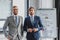 three handsome young businessmen in suits standing together and looking at camera