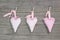 Three hanging hearts on a wooden board.