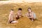 Three happy Caucasoid children in bathing suits build a tower of yellow sand on the beach