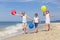 Three happy children with balloons playing on the beach at the d