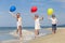 Three happy children with balloons playing on the beach at the d