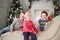 Three happy children in santa caps lie on couch