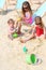 Three happy children sit on beach and play with