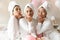 Three happy diverse young girls wear bathrobes blowing kisses, portrait