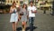 Three happy friends drinking coffee while walking around the city. Full height portrait of two girls and one boy with