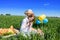 Three happy kids sitting on picnic on the field. blue sky, green grass. bread, pies and fruits in a basket.