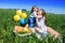 Three happy kids sitting on picnic on the field. blue sky, green grass. bread, pies and fruits in a basket.