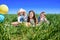 Three happy kids sitting on picnic on the field. blue sky, green grass. bread, pies and fruits in a basket.