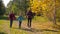 Three happy kids walking together in sunny autumn forest