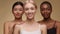 Three happy ladies smiling to camera, asian and african american women touching shoulder of their caucasian friend
