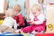 Three happy mothers watching their babies playing with safe multicolored toys