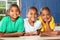 Three happy school girls reading a book in class