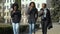 Three happy young african american girls drinking coffee from paper cup walking down the street