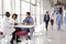 Three healthcare workers talking in a busy modern lobby