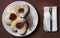 Three heart-shaped cookies with jam on a plate. Napkin and fork