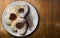 Three heart-shaped cookies with jam on a plate on wooden table background