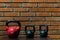 three heavy dumbbells stand as a background, on a brick wall, for a cross-fit