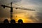 Three helmet silhouette at construction site with crane background and sunset