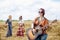 Three hippie women, wearing boho style clothes, dancing in the wheat field, playing guitar, laughing, Female friends, traveling