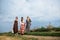 Three hippie women, wearing boho style clothes, walking on dirt road on green field, having fun. Female friends, traveling