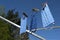 Three  homemade community face masks from cotton cloth after washing drying on a clothesline against a blue sky, protection