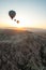 Three hot air baloons over a desert landscape at sunrise.