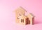 Three houses on a pink background. Buying and selling of real estate, construction. Apartments and residential buildings in a city