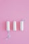 Three hygienic tampons on a pink background.