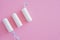 Three hygienic tampons on a pink background.