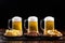 Three ice-cold beer mugs and plates with appetizers on wooden base on black background